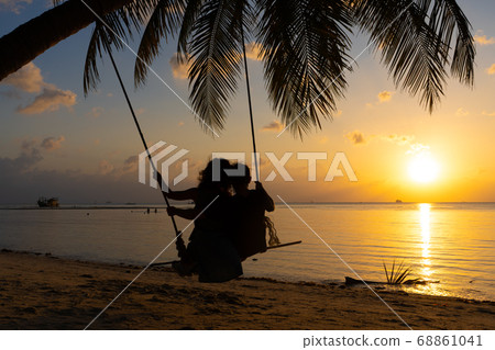 Silhouetted couple in love walks on the beach Silhouetted couple in love walks on the beach 68861041