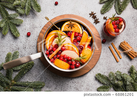Mulled wine with cinnamon, cranberry, orange in ladle and glass on grey table. 68861201