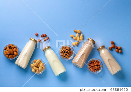 Bottles of vegan non dairy milk with various nuts on blue background Bottles of vegan non dairy milk with various nuts on blue background 68861630
