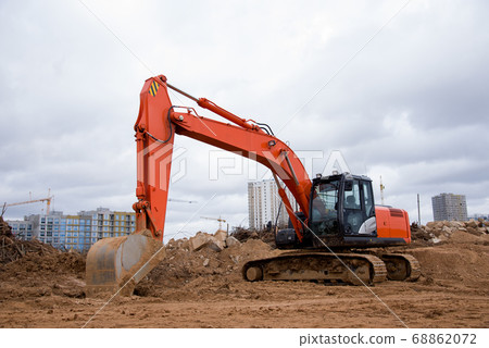 Red excavator during earthworks at construction site 68862072