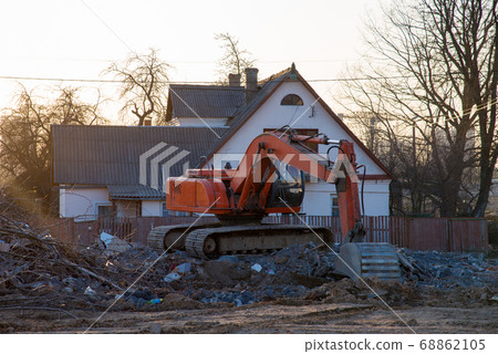 Excavator demolishes an old wooden house in the village for new construction project Excavator demolishes an old wooden house in the village for new construction project 68862105