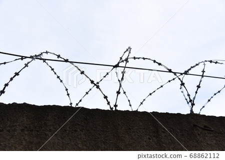 Fence with barbed wire against a blue sky background 68862112
