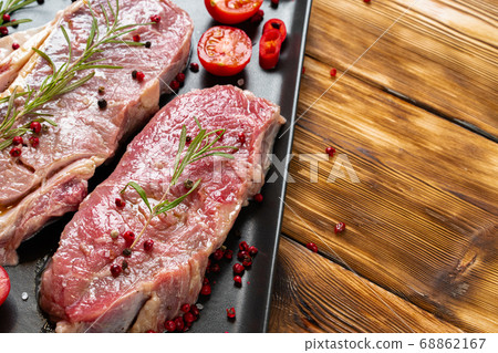 Two raw beef steaks on dark wooden table Two raw beef steaks on dark wooden table 68862167