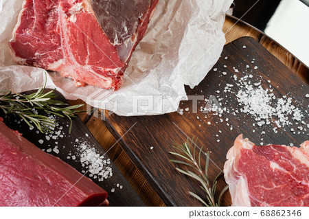 Raw T-bone steak with herbs on wooden board Raw T-bone steak with herbs on wooden board 68862346