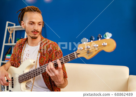 Young caucasian man with dreadlocks playing electric guitar in his room 68862489