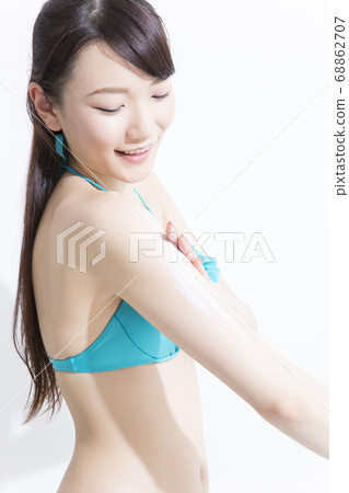 A woman in a swimsuit wearing sunscreen A woman in a swimsuit wearing sunscreen 68862707