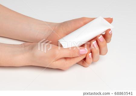 Female hand holding cosmetic bottle on white Female hand holding cosmetic bottle on white 68863541
