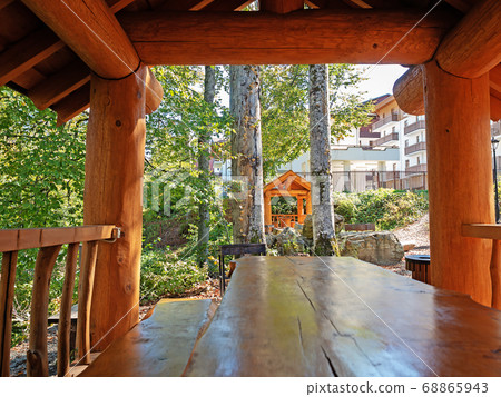 View from a wooden gazebo on trees with green foliage, a picnic area and a house View from a wooden gazebo on trees with green foliage, a picnic area and a house 68865943