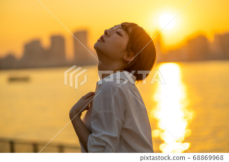 Young woman nestling with dramatic sunset Young woman nestling with dramatic sunset 68869968