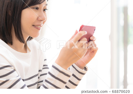 A woman watching a smartphone A woman watching a smartphone 68870020