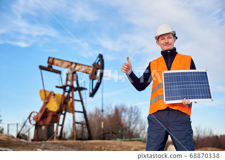 Oil man holding solar panel and giving thumbs up. Oil man holding solar panel and giving thumbs up. 68870338