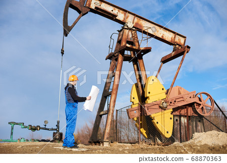 Petroleum engineer controlling work of oil well pump jack. 68870363