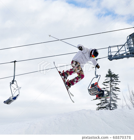 Young man on skis jumping in the air at ski resort. 68870378