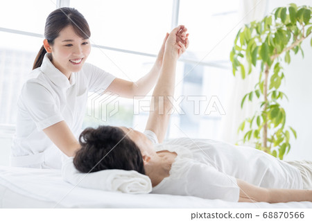 Medical senior woman doing gymnastics with physical therapist 68870566