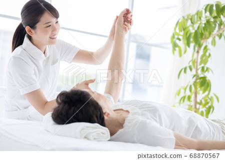 Medical senior woman doing gymnastics with physical therapist 68870567