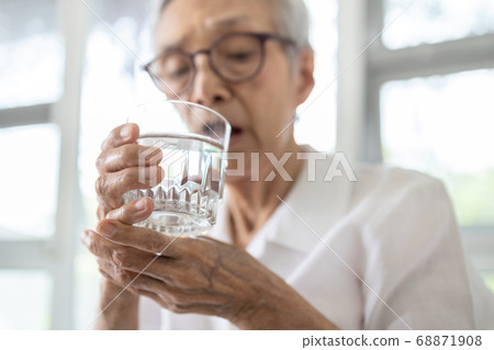 Senior woman holding glass of water,hand shaking while drinking water,elderly patient with hands tremor uncontrolled body tremors,symptom of essential tremor,parkinson's disease,neurological disorders 68871908