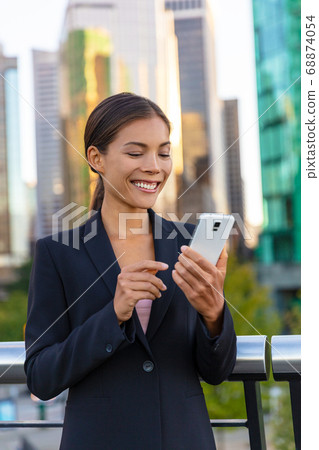 Woman using phone - Asian businesswoman holding smartphone texting on messenger app online to businesspeople. Working outside walking in city street. Happy Chinese Caucasian biracial lady Woman using phone - Asian businesswoman holding smartphone texting on messenger app online to businesspeople. Working outside walking in city street. Happy Chinese Caucasian biracial lady 68874054