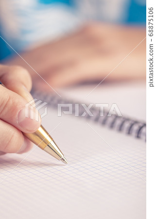 Teen writes black yellow pen in a checkered notebook. Exam at school 68875106