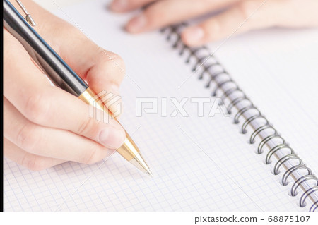 Man's hand with a black-gold pen over a clean sheet of checkered notebook. Writing a diary for business ideas Man's hand with a black-gold pen over a clean sheet of checkered notebook. Writing a diary for business ideas 68875107