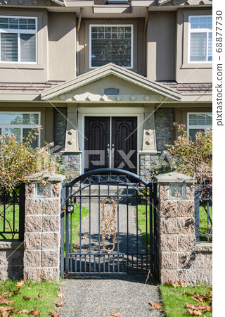 Entrance of luxury residential house with big front yard behind the grid fence Entrance of luxury residential house with big front yard behind the grid fence 68877730