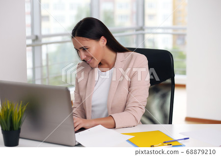 Young happy businesswoman in office, working on laptop Young happy businesswoman in office, working on laptop 68879210
