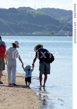 Family walking hand in hand on the sandy beach Family walking hand in hand on the sandy beach 68879449