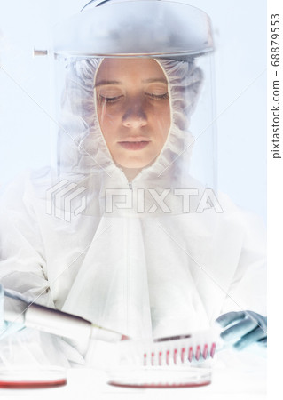 Female scientist working in the corona virus vaccine development laboratory research with a highest degree of protection gear. Female scientist working in the corona virus vaccine development laboratory research with a highest degree of protection gear. 68879553