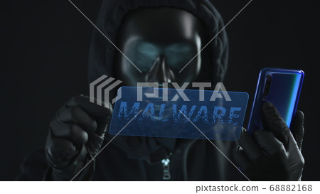 Hacker wearing black mask pulls MALWARE tab from a smartphone. Hacking concept 68882168