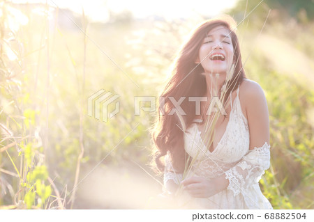 portrait of beautiful woman having a happy time and enjoying among grass field in nature portrait of beautiful woman having a happy time and enjoying among grass field in nature 68882504