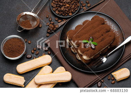 Classic tiramisu dessert and savoiardi cookies on ceramic plate on concrete background 68883130