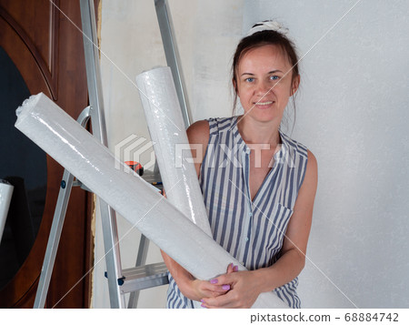 Woman in rolls of Wallpaper in the room. Preparation for repairs in the apartment. Woman in rolls of Wallpaper in the room. Preparation for repairs in the apartment. 68884742