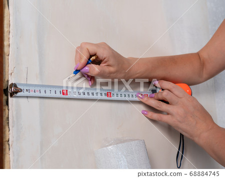 Measuring the walls in the room before pasting Wallpaper close-up. Measuring the walls in the room before pasting Wallpaper close-up. 68884745