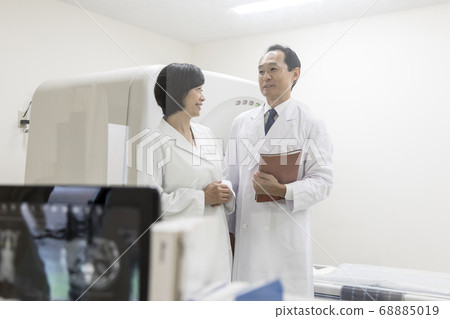 Doctor and operator meeting in front of CT (through window) 68885019