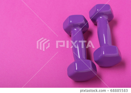 two lilac dumbbells lie on a lilac background, concept, copy space two lilac dumbbells lie on a lilac background, concept, copy space 68885583