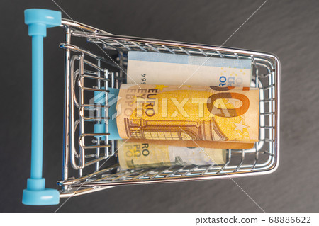 Banknotes euro in mini shopping trolley. Shopping cart concept or business. Banknotes euro in mini shopping trolley. Shopping cart concept or business. 68886622