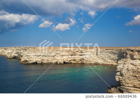 beautiful white rocks in a blue sea with boats 68889436