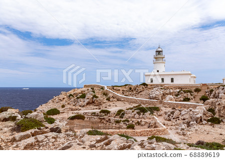 Beautiful seascape with a lighthouse (Faro de Cavalleria) on a cliff and a cruise ship in the sea. Beautiful seascape with a lighthouse (Faro de Cavalleria) on a cliff and a cruise ship in the sea. 68889619