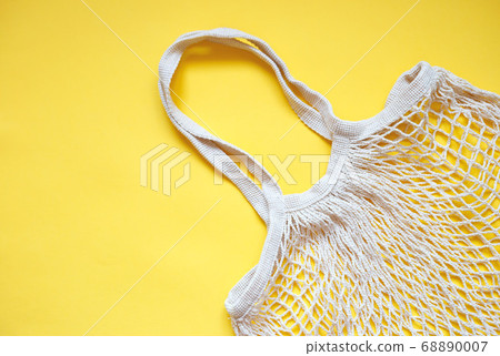 Beige cotton string knitted bag on yellow Beige cotton string knitted bag on yellow 68890007