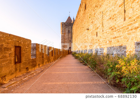 Wide fortified walls with walkways and arches of medieval castle of Carcassonne town at sunset 68892130