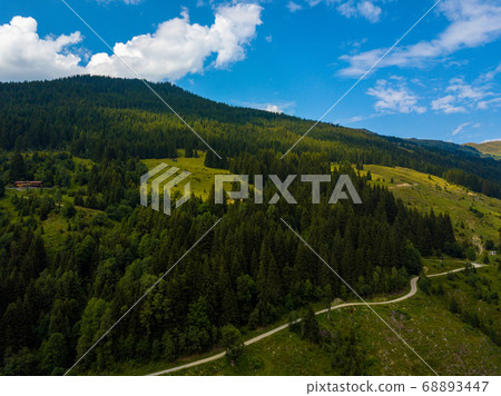 Aerial view on cozy hut and mountain in the skiing region of Hinterglemm in the Alps in Austria on a sunny summer day Aerial view on cozy hut and mountain in the skiing region of Hinterglemm in the Alps in Austria on a sunny summer day 68893447