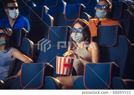 Cinema, movie theatre during quarantine. Coronavirus pandemic safety rules, social distance during movie watching Cinema, movie theatre during quarantine. Coronavirus pandemic safety rules, social distance during movie watching 68893522
