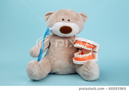 Stuffed Bear animal with toothbrush as a symbol of children dentistry concept isolated on blue Stuffed Bear animal with toothbrush as a symbol of children dentistry concept isolated on blue 68893969
