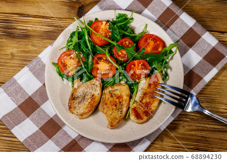 Fried chicken breast with salad of fresh arugula Fried chicken breast with salad of fresh arugula 68894230