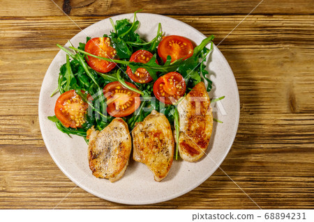 Fried chicken breast with salad of fresh arugula Fried chicken breast with salad of fresh arugula 68894231