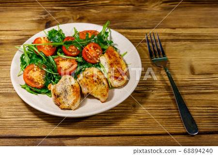 Fried chicken breast with salad of fresh arugula 68894240