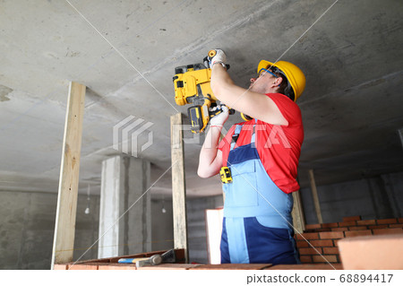 Builder works with special equipment on ceiling 68894417