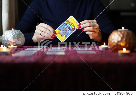 Tarot reader picking tarot cards near burning candles. Tarot reader picking tarot cards near burning candles. 68894806