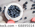Cup with blueberries near macaroons 68895014
