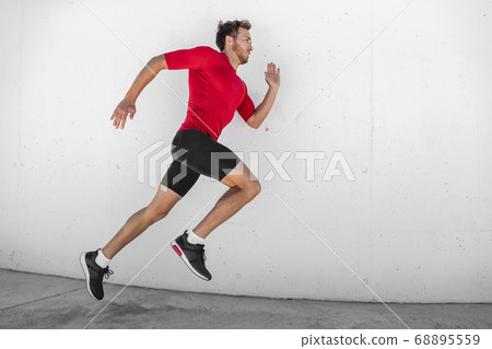 Run race athlete running man sprinting fast profile sideways against white wall outdoor background. Male runner training glutes and legs muscles healthy active lifestyle Run race athlete running man sprinting fast profile sideways against white wall outdoor background. Male runner training glutes and legs muscles healthy active lifestyle 68895559