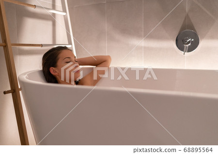 Luxury bathtub Asian woman relaxing in home spa taking a bath shower showering for total relaxation. Young lady body care wellness sleeping in warm water, winter pampering Luxury bathtub Asian woman relaxing in home spa taking a bath shower showering for total relaxation. Young lady body care wellness sleeping in warm water, winter pampering 68895564